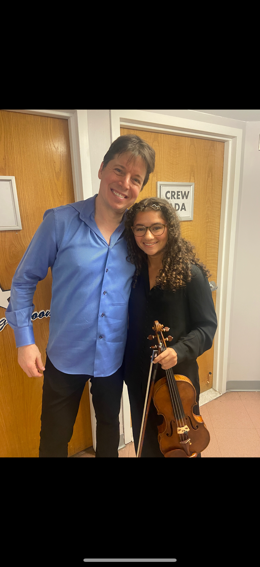 Victoria holding her violin backstage with violinist Joshua Bell